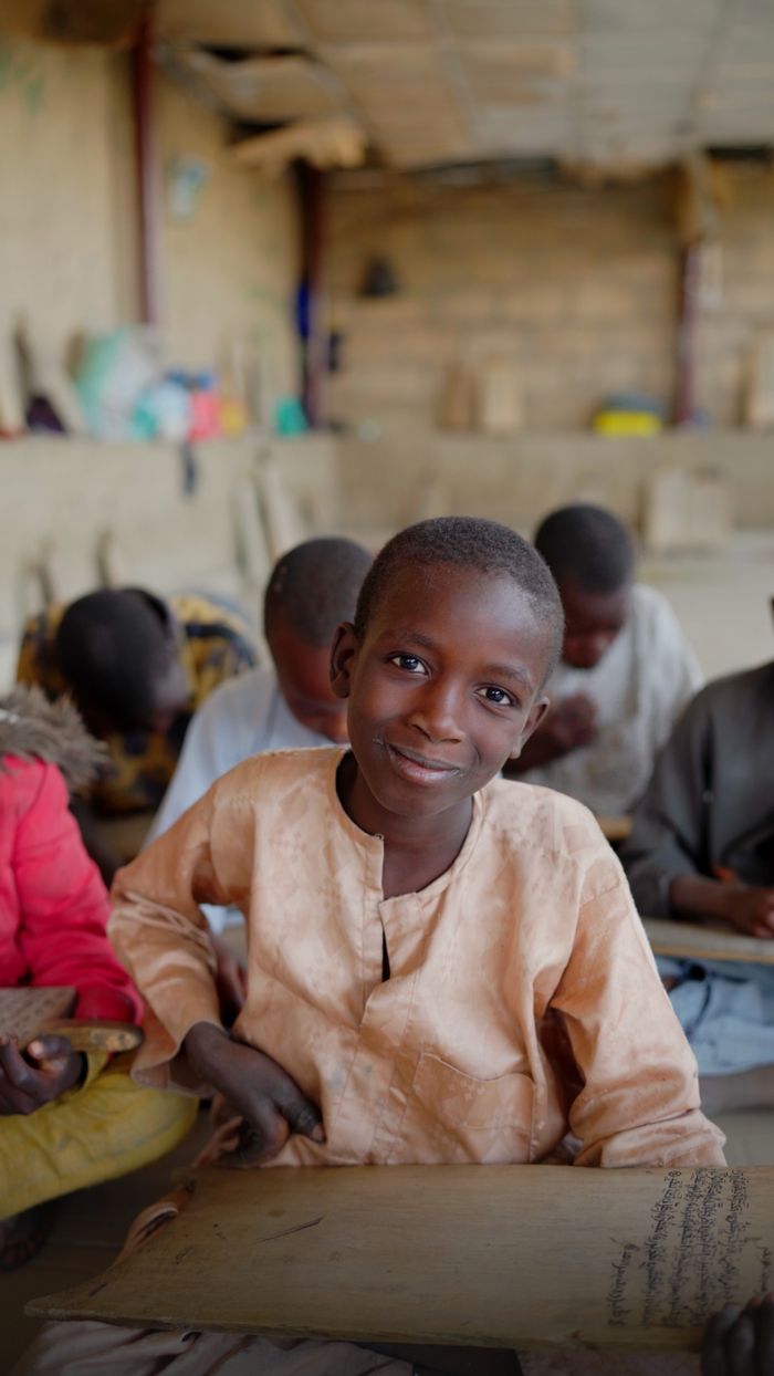 Young African boy smiling in a classroom, representing education and joy.